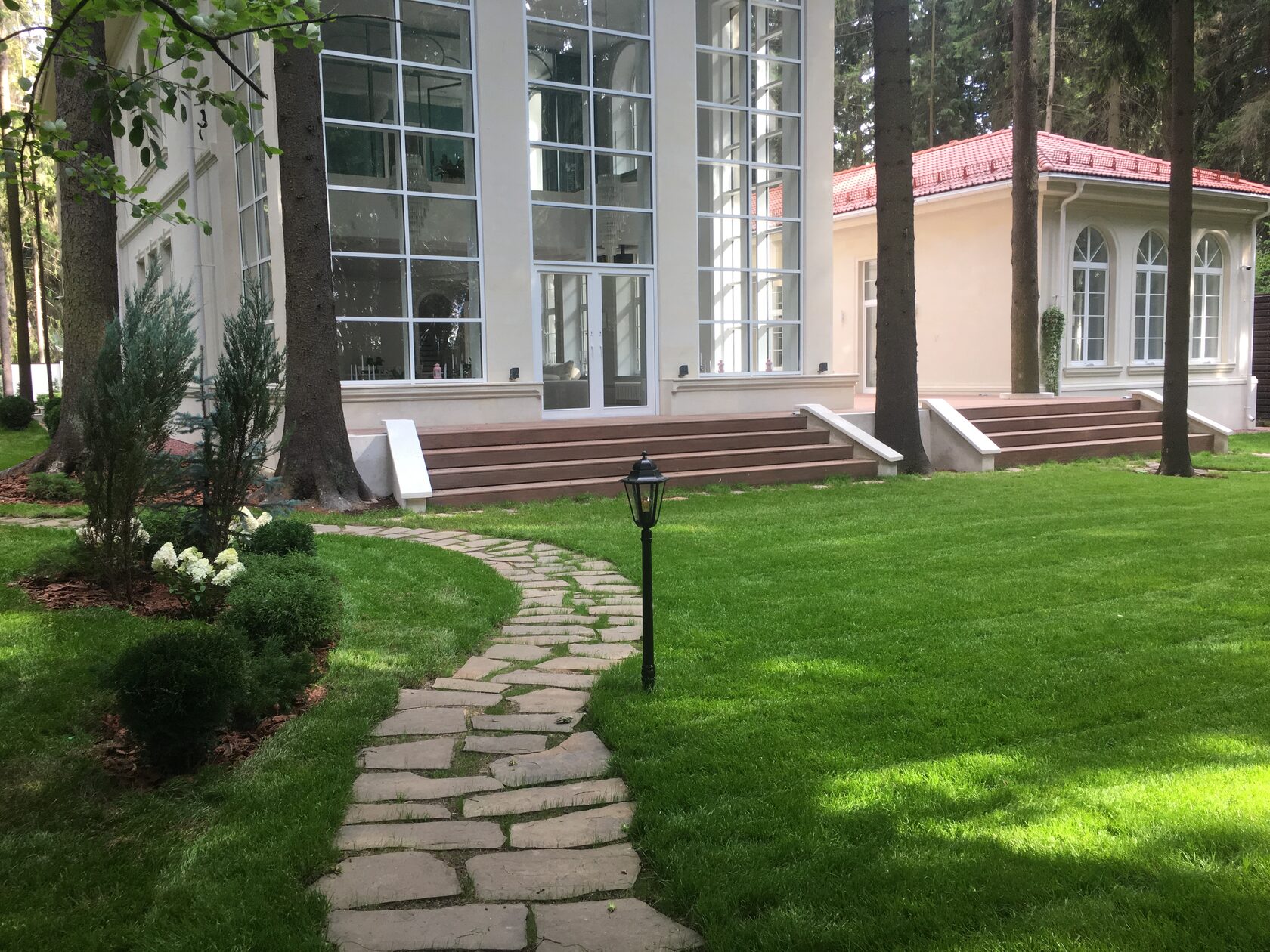 Современный дом с окружающим ландшафтом и газоном.